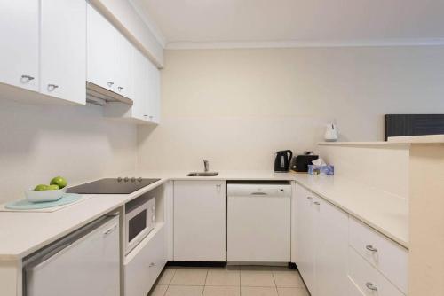 悉尼海滨大道一室公寓的白色的厨房配有白色橱柜和水槽