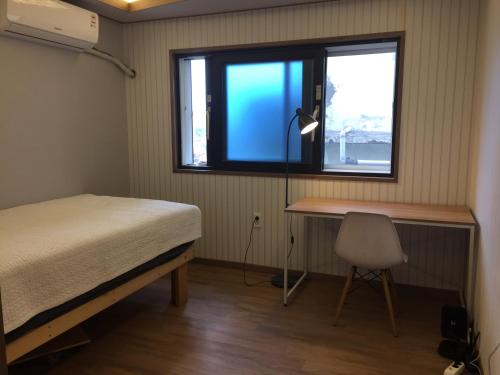 木浦市达尔古梅旅馆的一间卧室配有一张床、一张书桌和一个窗户。