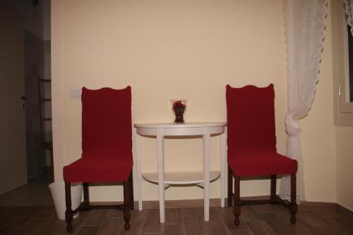 DorioEl Doorado的一张带两把红色椅子的白色桌子和一张带白色桌子的白色桌子