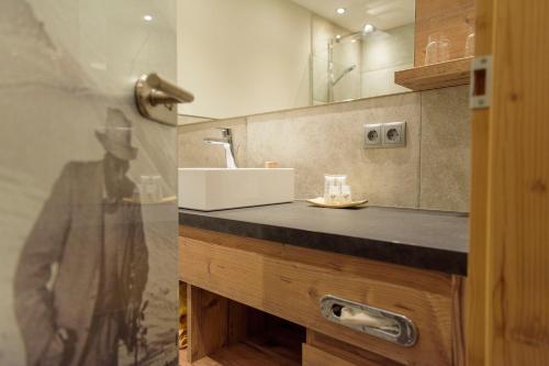 圣安东阿尔贝格圣安东尼奥公寓式酒店的浴室的柜台设有水槽和镜子