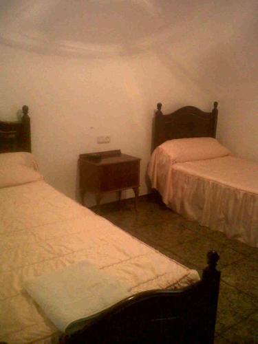 奥尔维拉Hostal Medina的一间卧室配有两张床,中间设有床头柜。