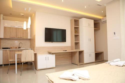 雅戈丁那Gold Crown Apartments的一间厨房,配有白色橱柜和墙上的电视