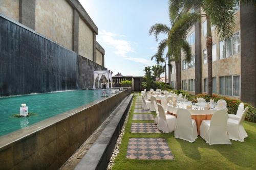 登巴萨ASTON Denpasar Hotel & Convention的游泳池旁的餐厅配有桌椅