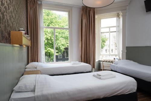 阿姆斯特丹阿姆斯特丹酒店的酒店客房设有三张床和窗户。