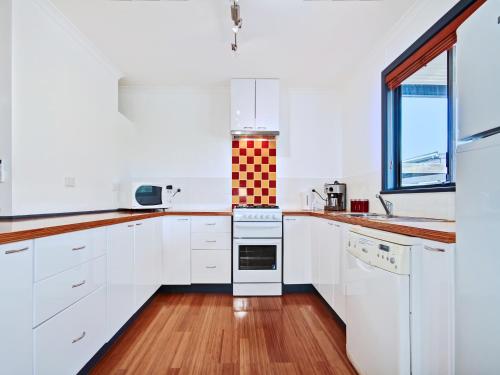 Port WillungaSea Devine - Port Willunga - C21 SouthCoast Holidays的厨房配有白色橱柜和炉灶烤箱。