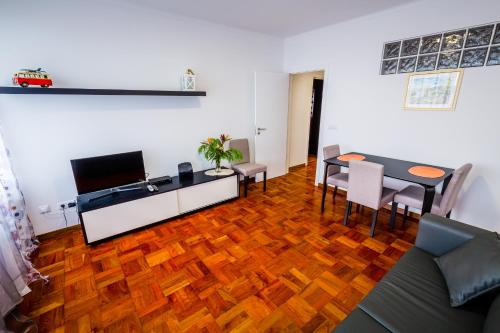 卡尼索Apartamento Vista Oceano的客厅铺有木地板,配有桌椅