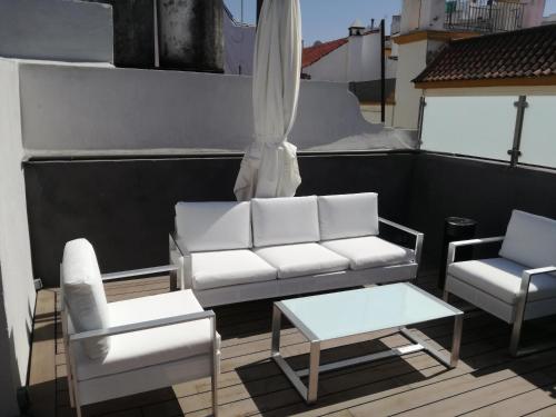 塞维利亚巴黎乐派酒店的阳台配有白色的沙发、两把椅子和一张桌子