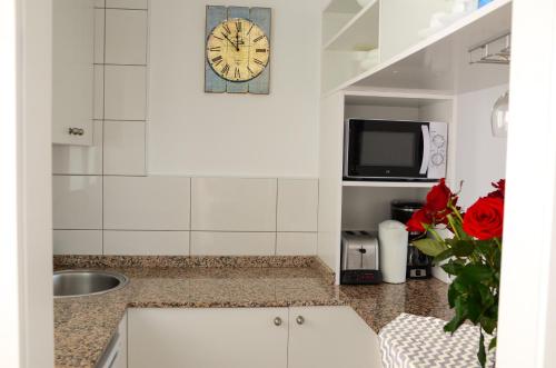 波多黎各Calypso Oasis Apartments的厨房配有水槽和墙上的时钟