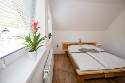 博希尼TriSa apartments Bohinj的一间卧室配有一张床和盆栽植物