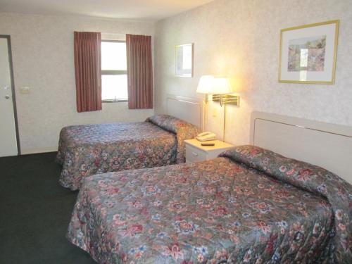 伊萨卡伊萨卡大使汽车旅馆的酒店客房,设有两张床和一盏灯