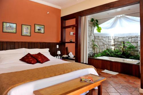 彼得罗波利斯金刚鹦鹉角酒店的一间卧室设有一张床和一个带浴缸的大窗户