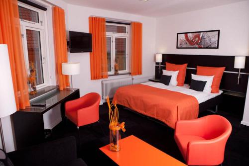 哈泽斯莱乌哈莫尼酒店的一间卧室配有红色的床和两张红色椅子