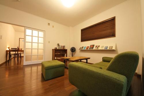 日光苏米卡公寓的客厅配有两张绿色椅子和一张桌子