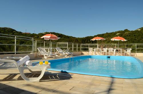 弗洛里亚诺波利斯华金海滩酒店 的一个带桌椅和遮阳伞的游泳池