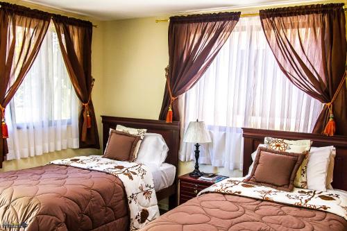 塔巴贝拉塔巴贝拉圣玛丽民宿的一间卧室设有两张床,窗户配有窗帘