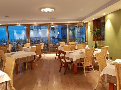 莱科HLL Hotel Lungolago Lecco-Como Lake的餐厅设有白色的桌椅和窗户。