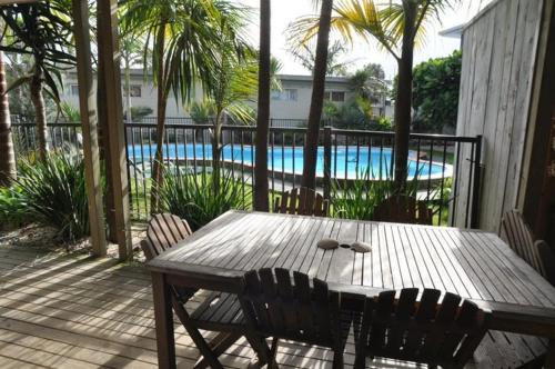 怀普怀普湾度假酒店的一个带游泳池的庭院里的一张木桌和椅子