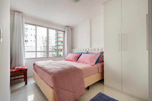 巴拉奈里奥-坎布里乌Apto 2 quartos, 1 quadra do Mar/Shop. Atlantico的一间卧室配有一张带粉色床单的床和一扇窗户。