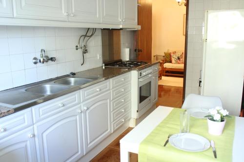 卡纳希迪Mary's House的厨房配有白色橱柜、水槽和桌子