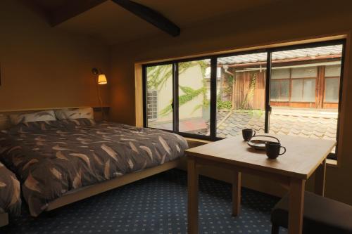 宫津市宫津萨卡拉度假屋的一间卧室配有一张床、一张桌子和一个窗户。