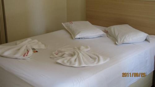 卡斯卡韦尔Hotel Joia的一张带两个枕头的白色床和毛巾