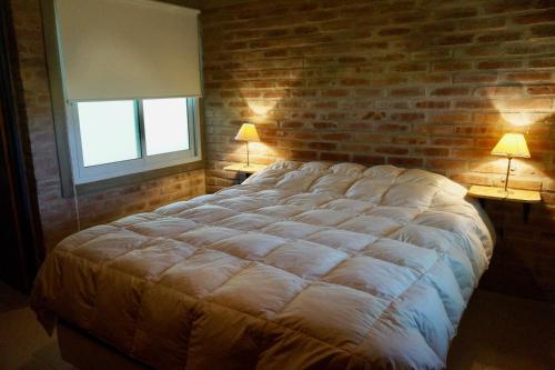 诺诺圣塔梅特宾馆的一间卧室设有一张带砖墙的大床
