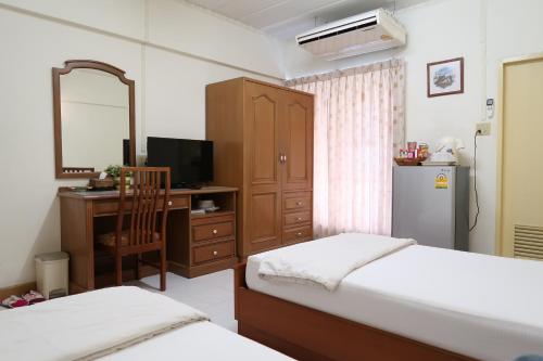 曼谷Phawana Sweet Hotel的一间卧室配有两张床、一张桌子和一台冰箱