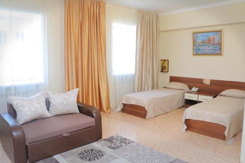 卡拉甘达祖穆拉特酒店的酒店客房,设有两张床、椅子和沙发
