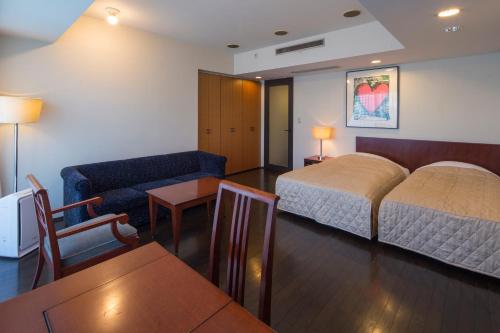 福冈福冈住宅套房酒店的酒店客房配有床、沙发和桌子。