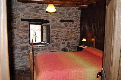 坎姆帕拉斯Apartaments turistics Moli Can Coll的一间卧室设有一张床和石墙