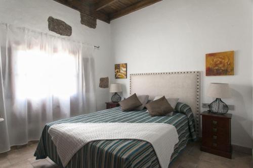 马赫Caserío Leandro III的一间卧室配有一张带条纹毯子的床和窗户