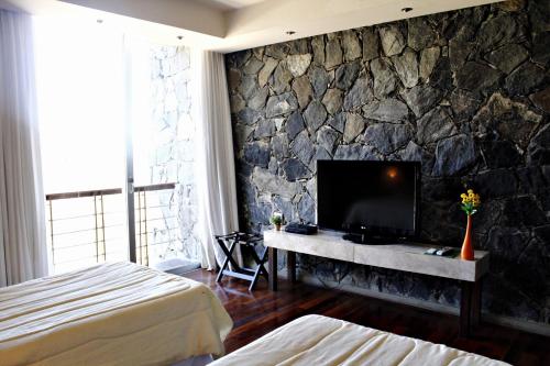 韦尔塔格兰德特雷斯皮尔卡斯酒店及水疗中心的一间卧室设有石墙和电视