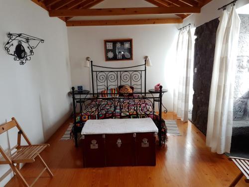 Calheta de NesquimAdega da Figueira的一间卧室设有一张黑色的床,铺有木地板。