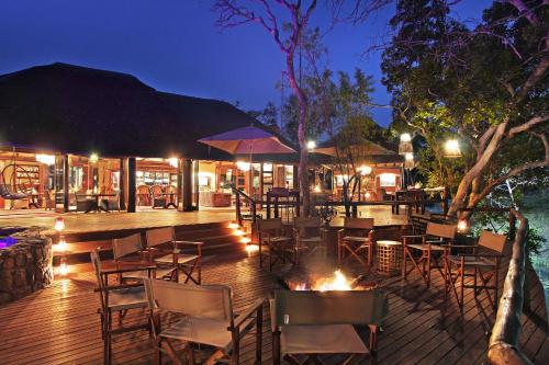 威尔吉旺登禁猎区Ndlovu Safari Lodge的一间晚上在甲板上摆放桌椅的餐厅