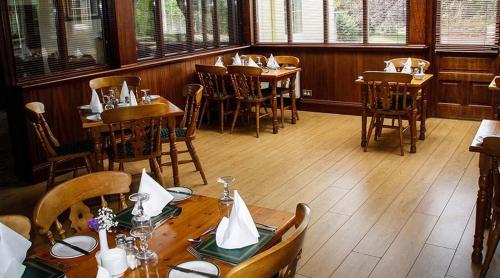 阿德莫尔Round Tower Hotel的餐厅设有木桌、椅子和窗户。