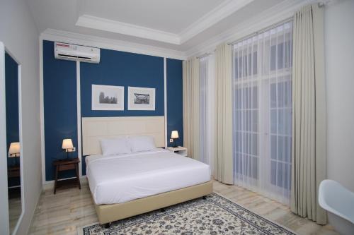 泗水鲁曼卡塔亚雅酒店的卧室配有白色的床和蓝色的墙壁