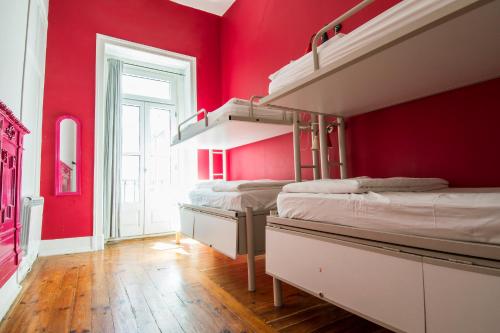 里斯本Safestay Lisbon Bairro Alto的一间设有三张双层床和红色墙壁的客房