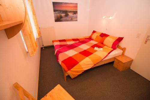 西里格Wangeroogeweg 5a的小卧室配有一张带色彩缤纷的被子的床