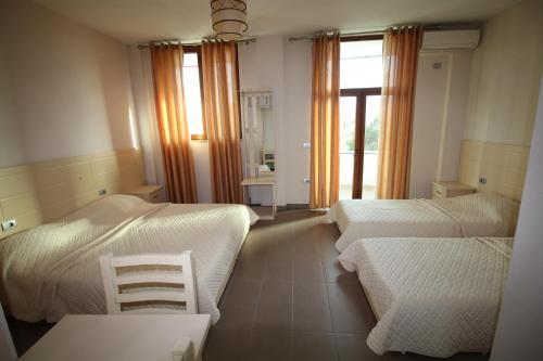 PeshkopiHotel Piazza的一间卧室设有两张床、两把椅子和窗户。