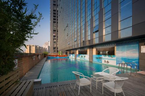 广州鸿德国际酒店的大楼内一个带两把椅子和一张桌子的游泳池