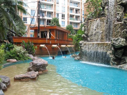 乔木提恩海滩亚特兰蒂斯度假公寓的一座位于瀑布的酒店中的游泳池,里面的人