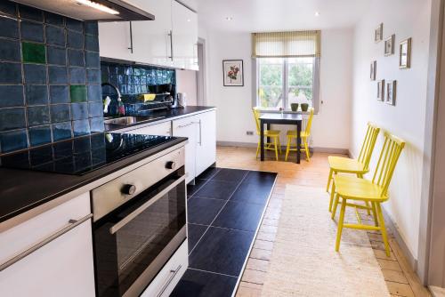 SköldingeEneby Gård Apartments的厨房配有白色橱柜和一张带黄色椅子的桌子