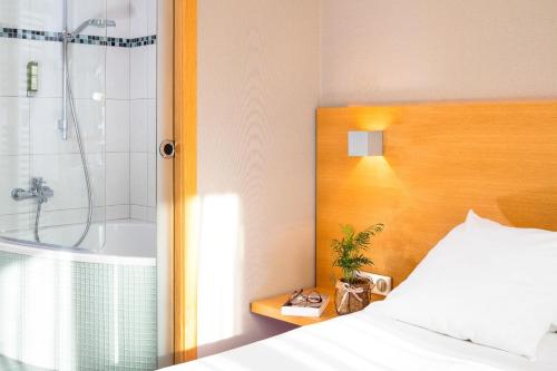 Carspach欧布尔森多为恩酒店的一间卧室配有一张床、淋浴和浴缸