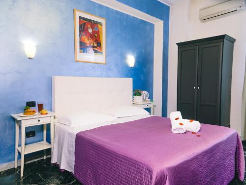 庞贝戴安娜住宿酒店的一间卧室配有一张带紫色毯子的床