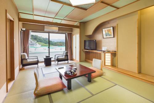 西伊豆町堂岛温泉日式旅馆的客厅配有桌子和电视