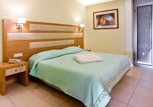 卡法斯爱琴海之梦酒店的一间卧室配有一张床,桌子上配有一部电话