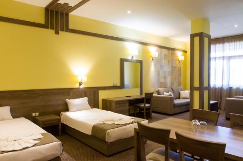 埃特罗波莱Hotel Etropolia的酒店客房带两张床、一张桌子和一张沙发