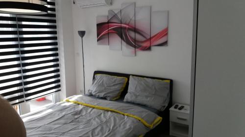 贝尔格莱德White City 1 Apartment的卧室配有一张床,墙上挂有绘画作品