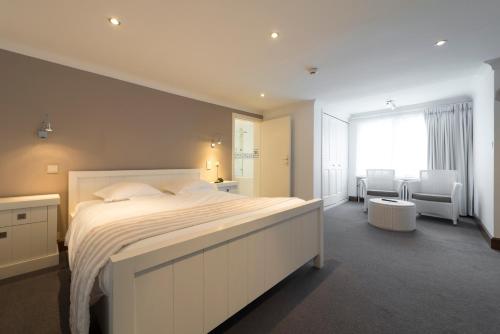 Corbion阿登酒店的一间卧室配有一张大床和一张桌子及椅子