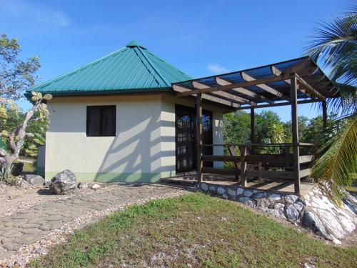 Cool ShadeGumbo Limbo Jungle Resort的一座白色的小建筑,设有绿色屋顶